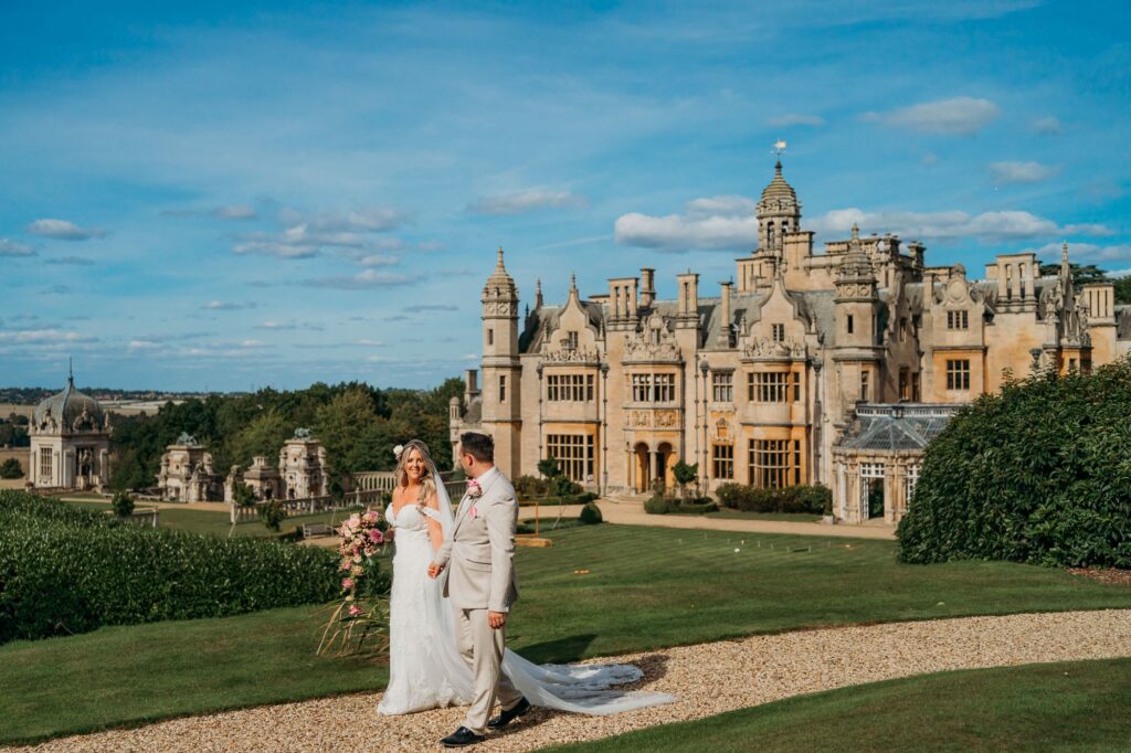 Bride and groom on a romantic walk with Harlaxton Manor behind them