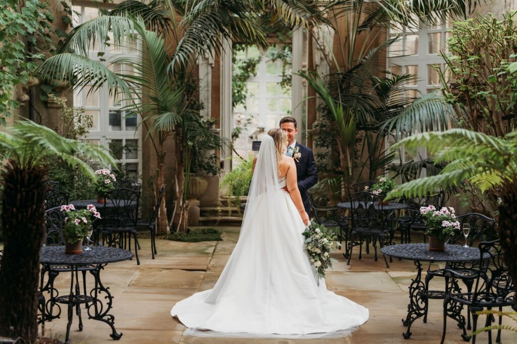 photograph of back of wedding dress with newlyweds stood in the Conservatory at Harlaxton Manor