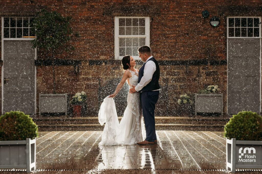 rainy wedding day photo at West Mill with bride and groom stood outside the front doors