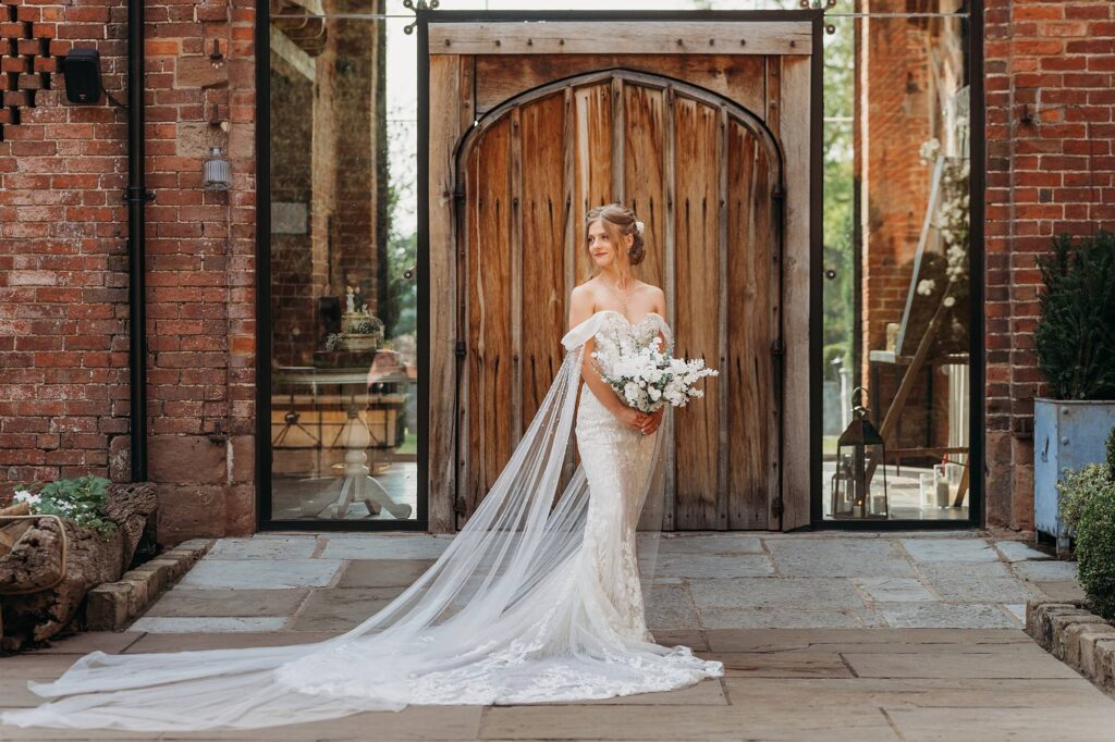 Beautiful bride stood outside barn doors at Shustoke Barn