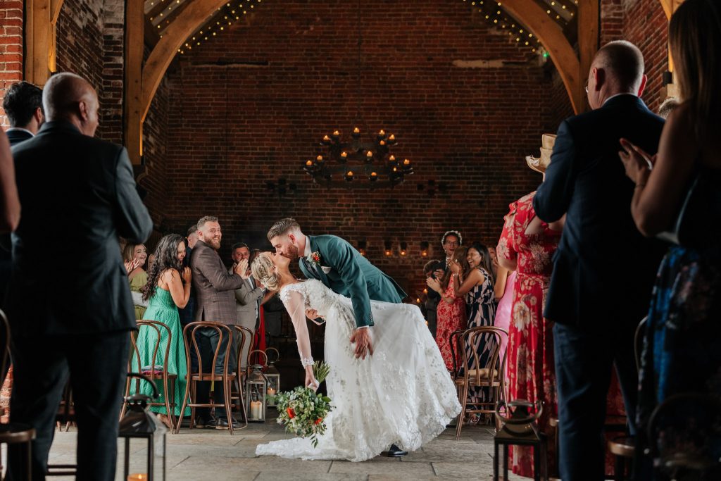 Bride & groom perform a stunning dip kiss whilst exiting from their wedding ceremony at Hazel Gap Barn